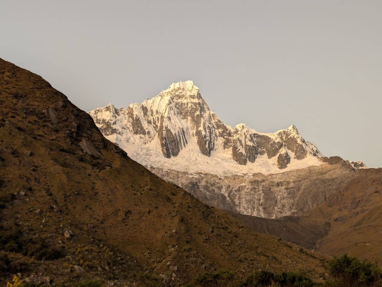 Photo du coucher de soleil aux couleurs chaudes sur le sommet du Taulliraju dans la Cordillère Blanche au Pérou