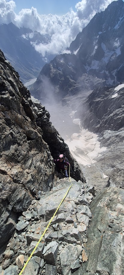 Alpiniste engagé dans le pilier sud de la Barre des Écrins, face à l’immensité de la paroi granitique en haute montagne