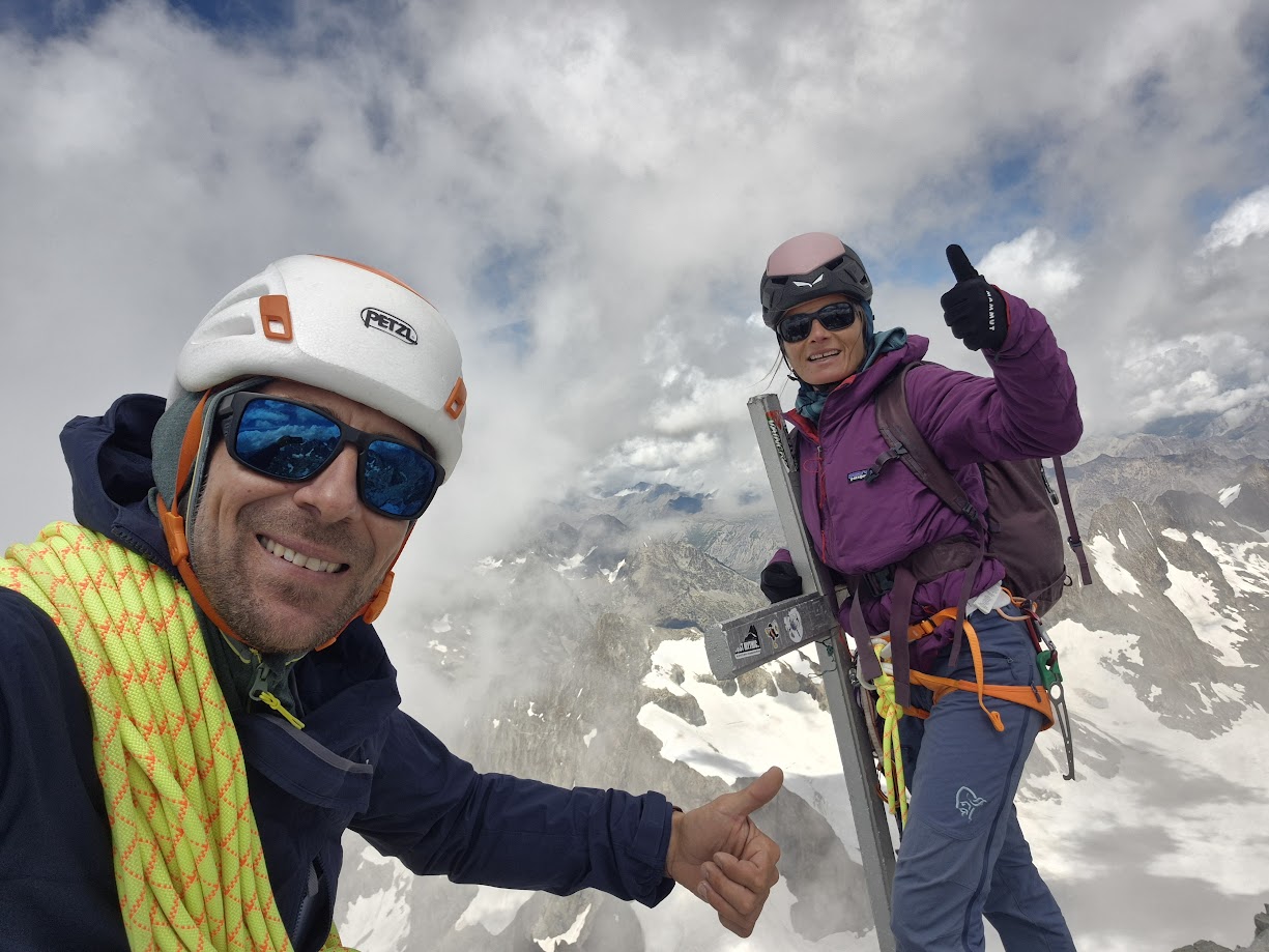 Deux alpinistes au sommet de la Barre des Écrins, près de la croix sommitale, heureux après l’ascension d’une face mythique