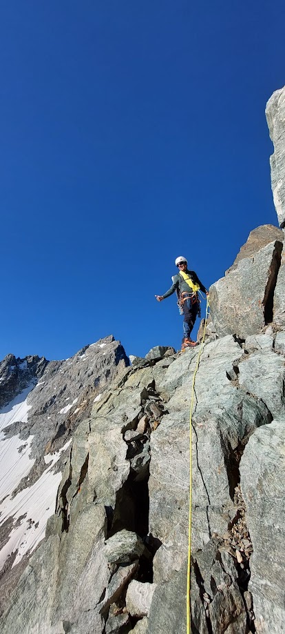 Alpiniste engagé dans le pilier sud de la Barre des Écrins, face à l’immensité de la paroi granitique en haute montagne