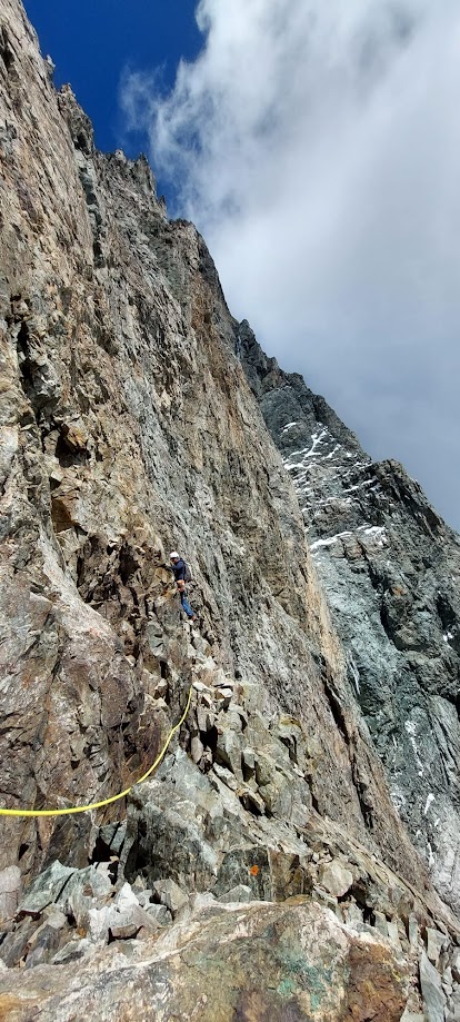 Alpiniste engagé dans le pilier sud de la Barre des Écrins, face à l’immensité de la paroi granitique en haute montagne