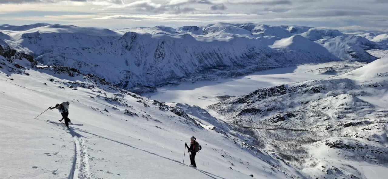 Montée en ski de randonnée dans le Finnmark en Norvège avec pente raide et vue sur les fjords enneigés