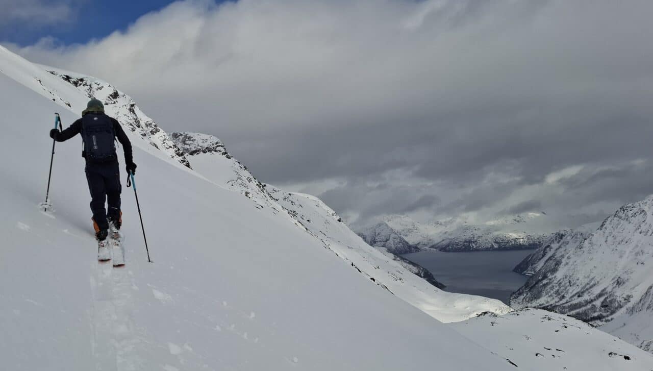 Skieur en montée en ski de randonnée au-dessus d’un fjord dans le Finnmark en Norvège lors du dernier jour