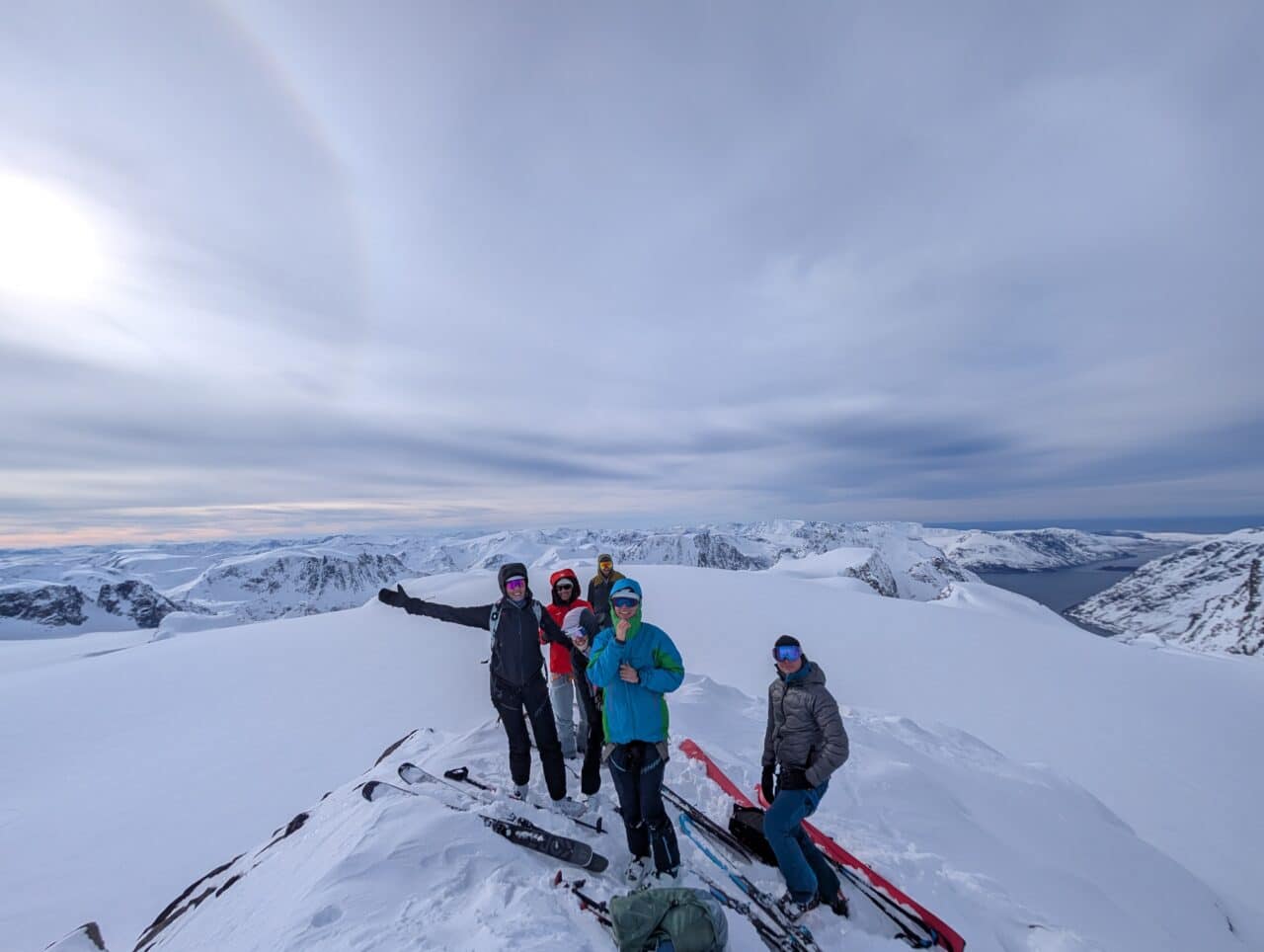 Groupe au sommet en ski de randonnée dans le Finnmark avec vue sur les fjords norvégiens enneigés