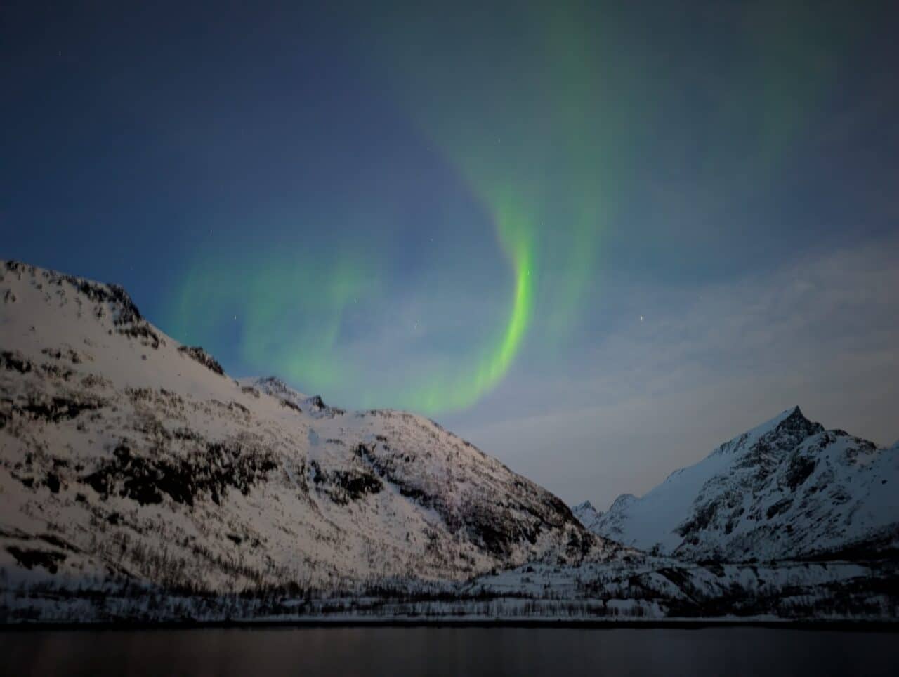 Aurore boréale au-dessus d’un fjord dans le Finnmark avec pente de ski de randonnée en Norvège