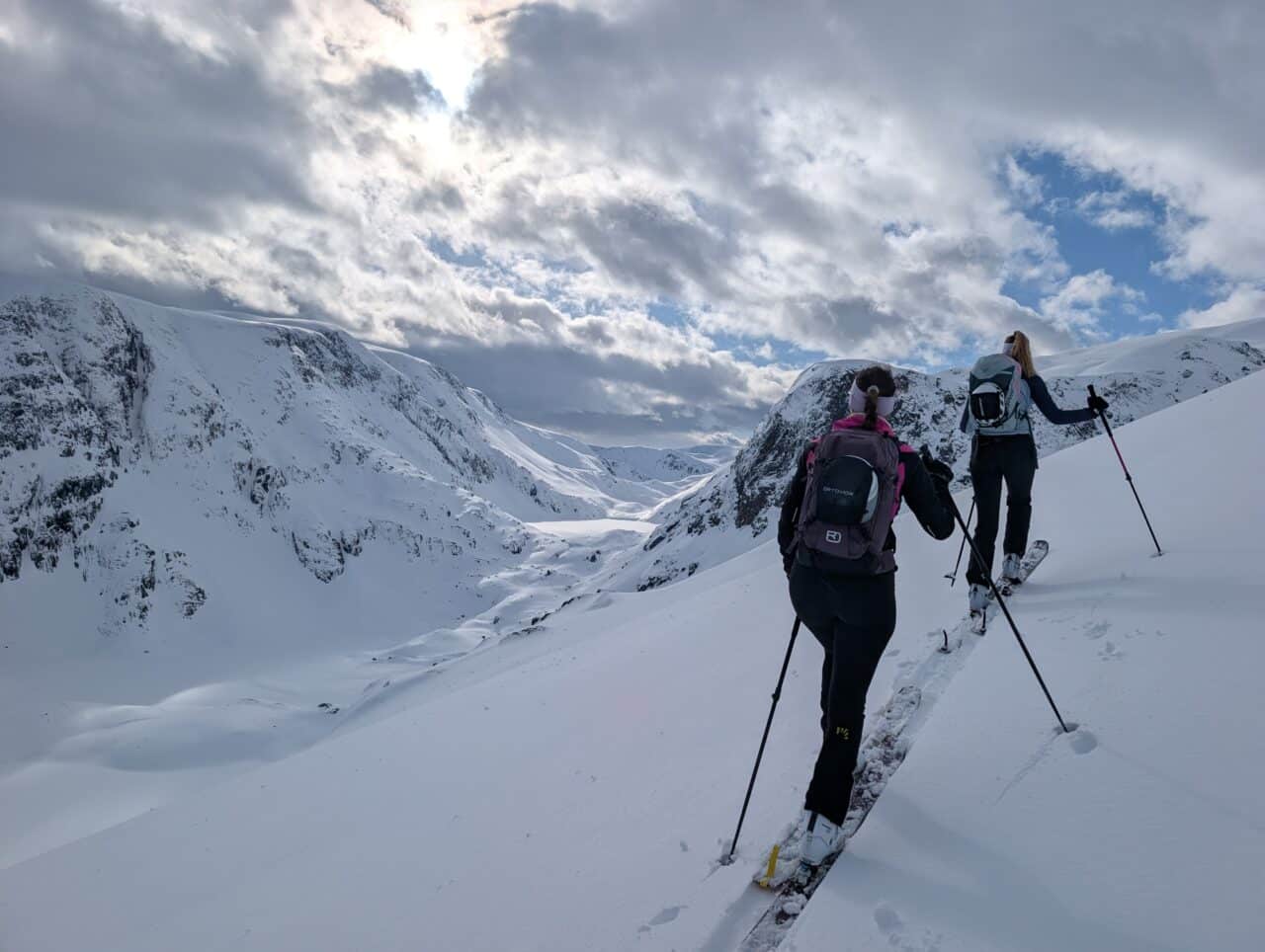 Skieurs en montée en ski de randonnée dans le Finnmark en Norvège avec ciel nuageux et éclaircies