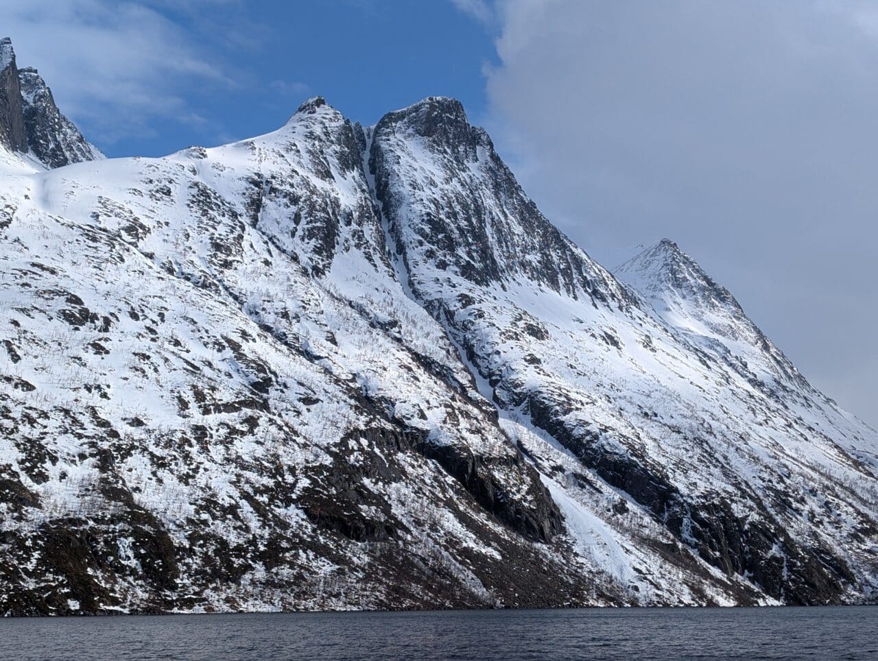 Couloir de ski raide dans le Finnmark en Norvège vu depuis un fjord avec montagnes enneigées