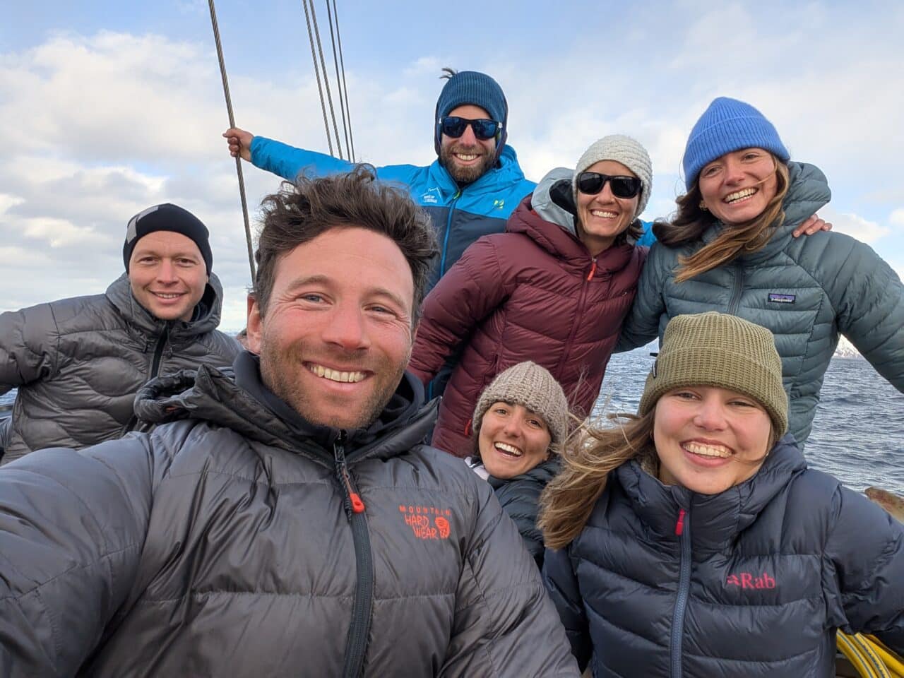 Groupe de skieurs souriants sur un bateau dans le Finnmark en Norvège lors d’un séjour de ski de randonnée