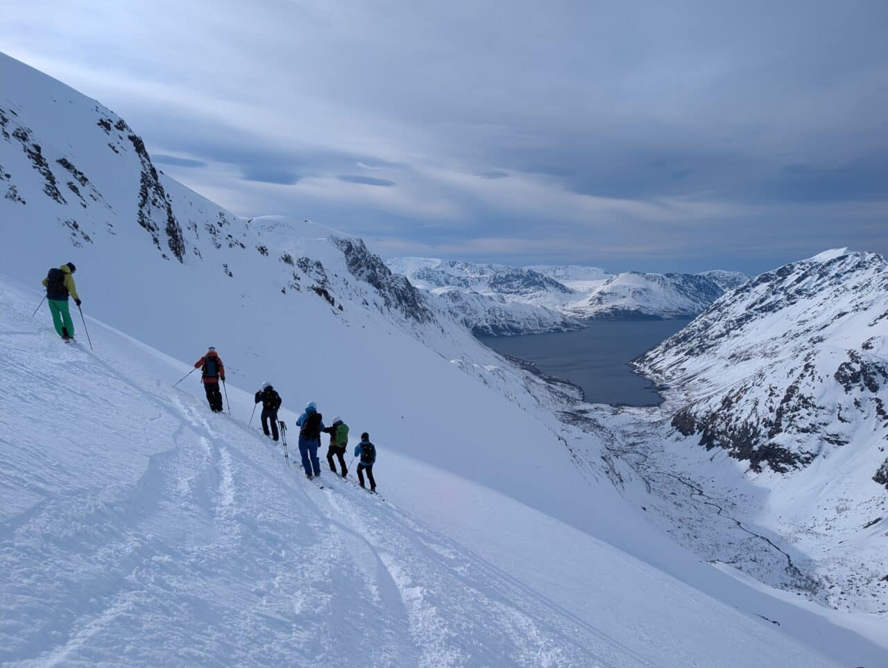 Skieurs en descente vers un fjord dans le Finnmark en Norvège en ski de randonnée avec vue sur la mer