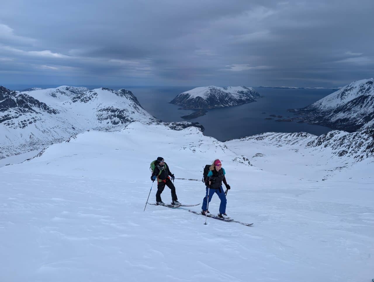Skieurs en montée au-dessus de la mer dans le Finnmark en Norvège sous un ciel contrasté en ski de randonnée