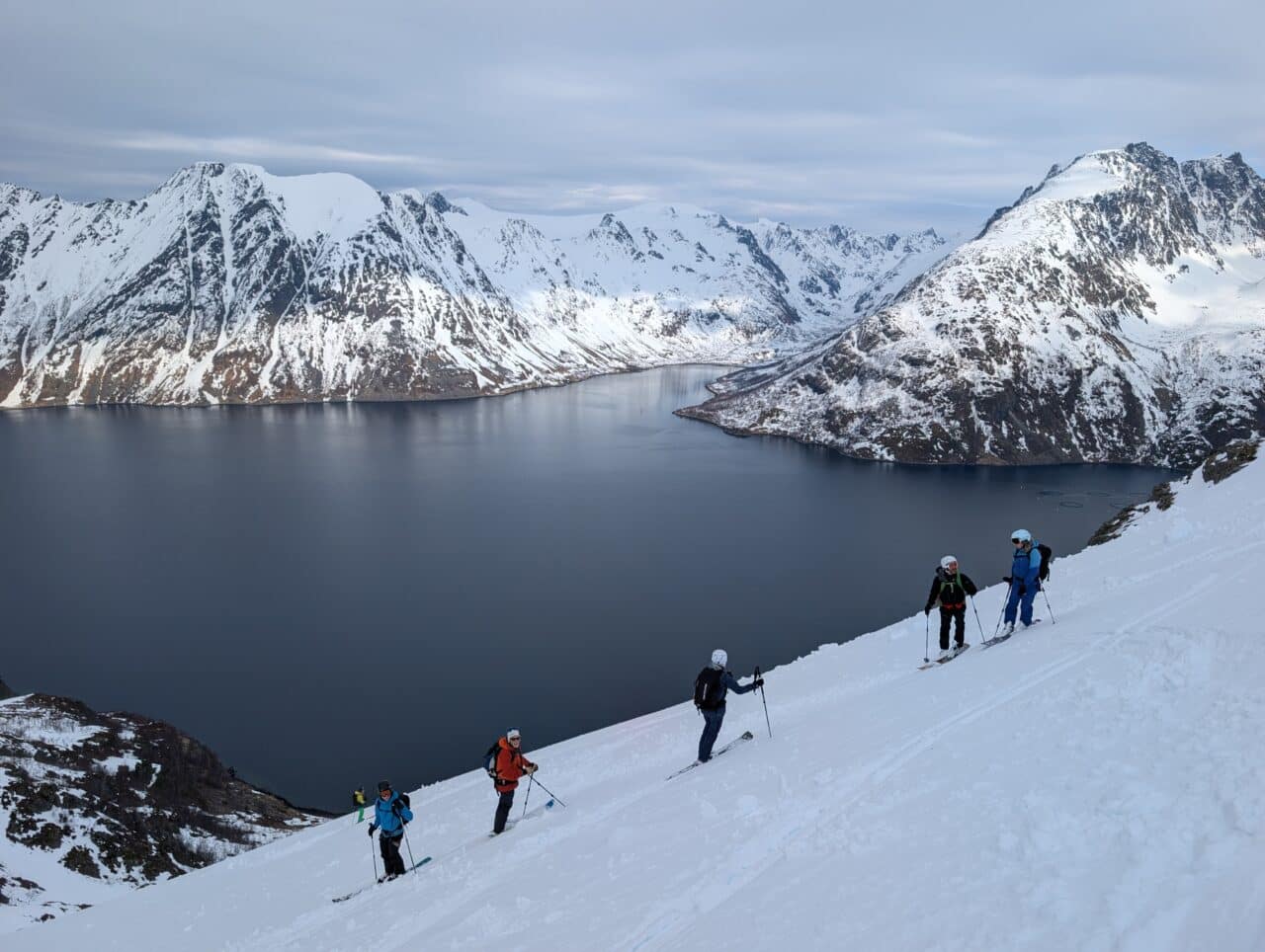 Skieurs en descente au-dessus d’un fjord dans le Finnmark en Norvège avec vue sur la mer en ski de randonnée