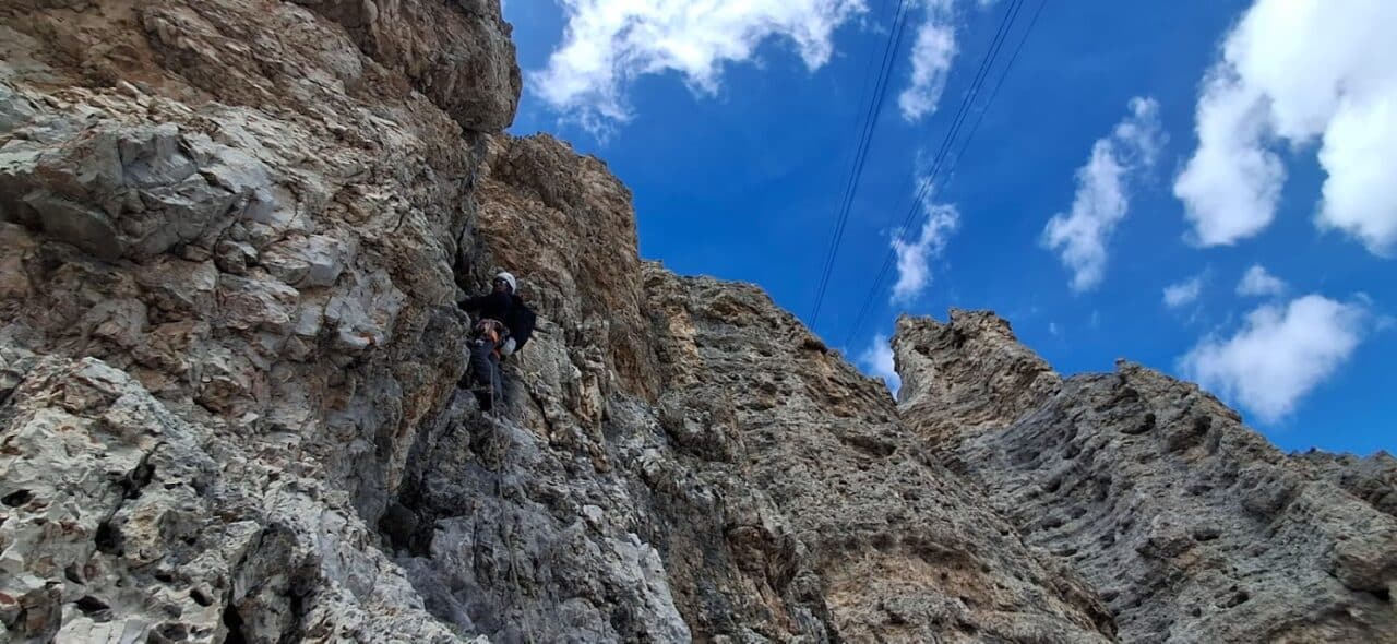 Grimpeur évoluant dans une longueur aérienne de la voie Gross-Momoli sur les parois calcaires du Sass Pordoi dans les Dolomites italiennes.