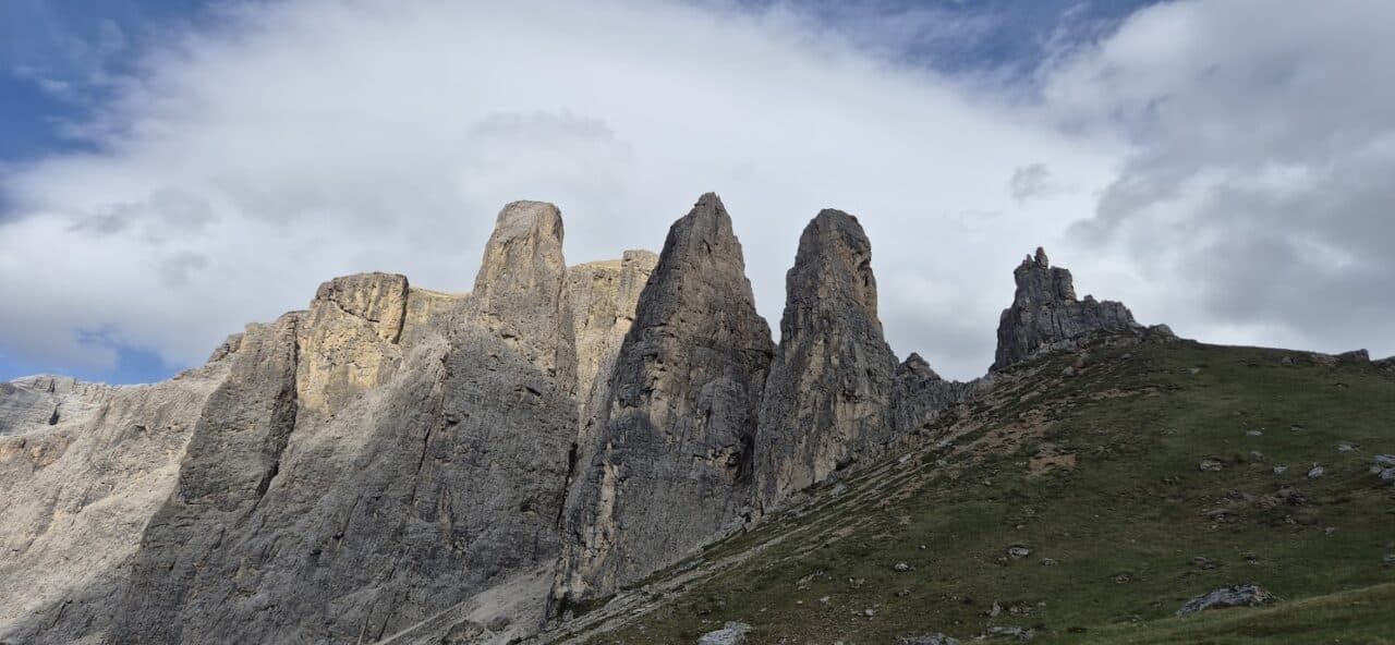 Vue panoramique des impressionnantes Tours de Sella dans les Dolomites, avec leurs parois rocheuses abruptes dominant les alpages alpins.
