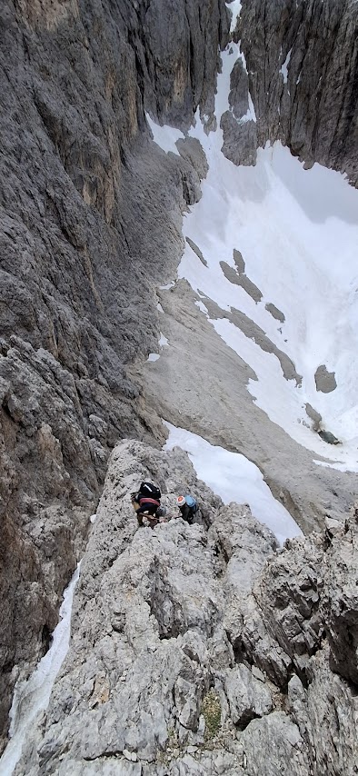 Alpiniste progressant sur les rochers de la voie normale du Sassolungo après le franchissement du glacier central dans les Dolomites italiennes.