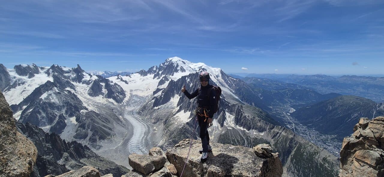 Grimpeur au sommet du Grand Dru dans le massif du Mont‑Blanc, après une ascension alpine engagée